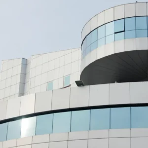 A sleek commercial building with a curved, multi-story glass facade and light grey panels.